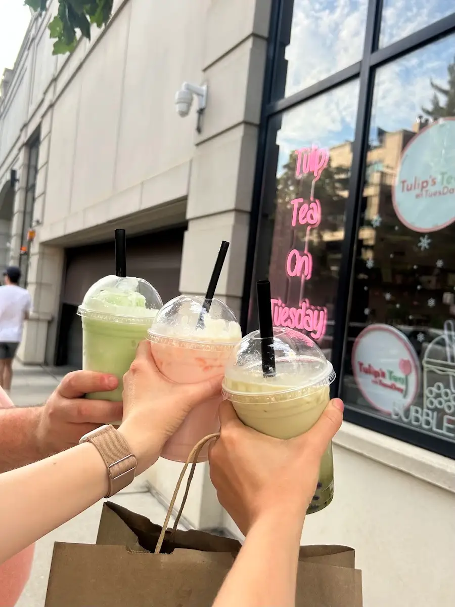 Three friends toasting with matcha drinks outside the shop
