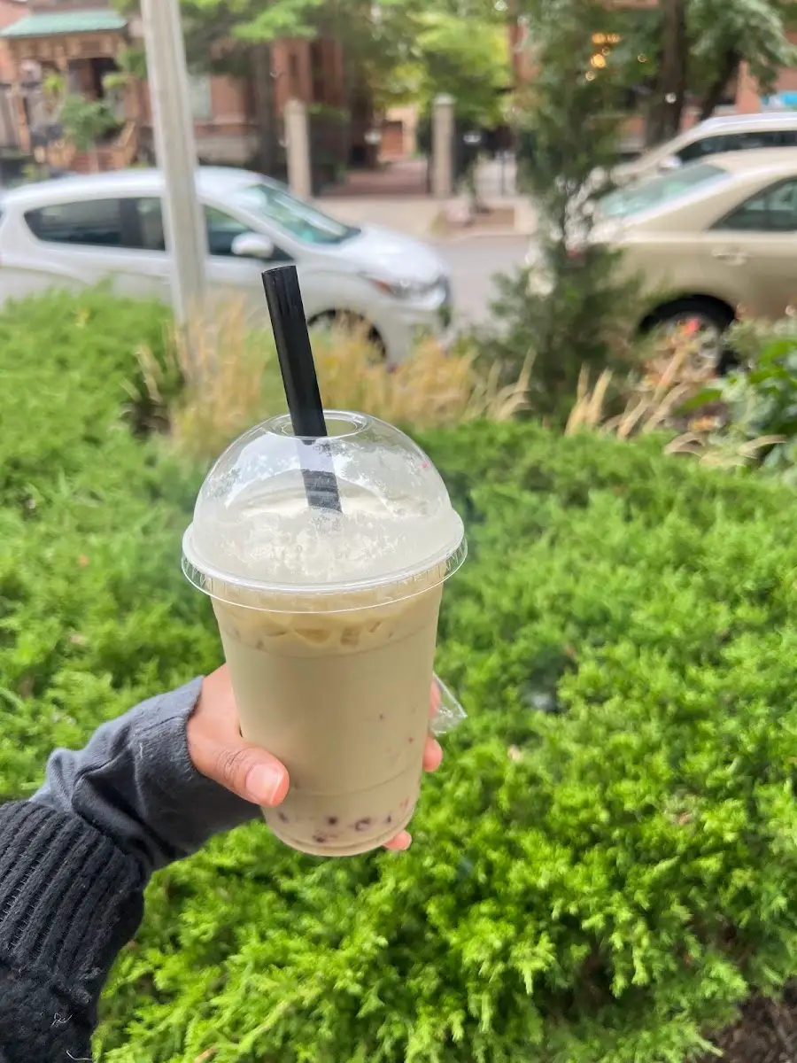 Iced matcha latte with boba held up outside